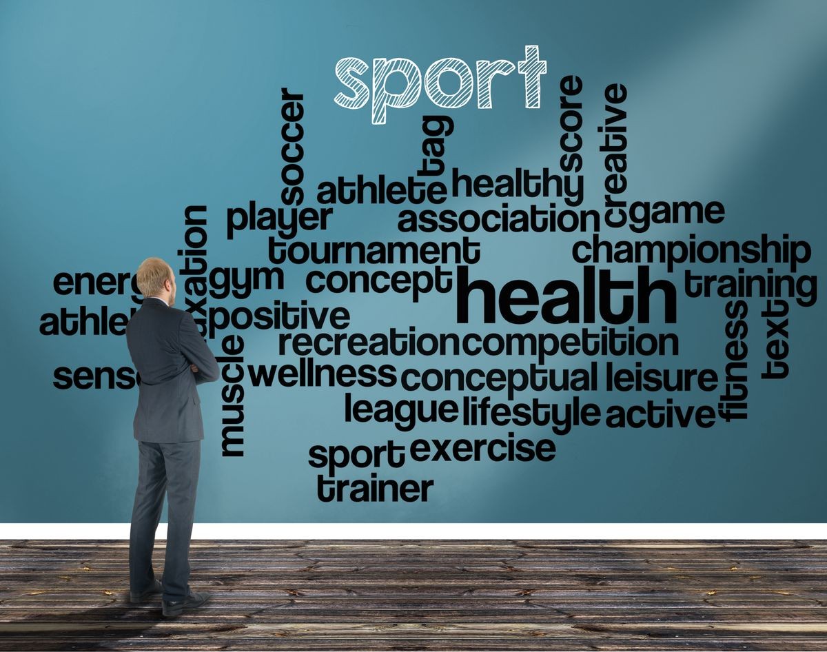 businessman in a room looking at a wall of which is the wordcloud related to sport