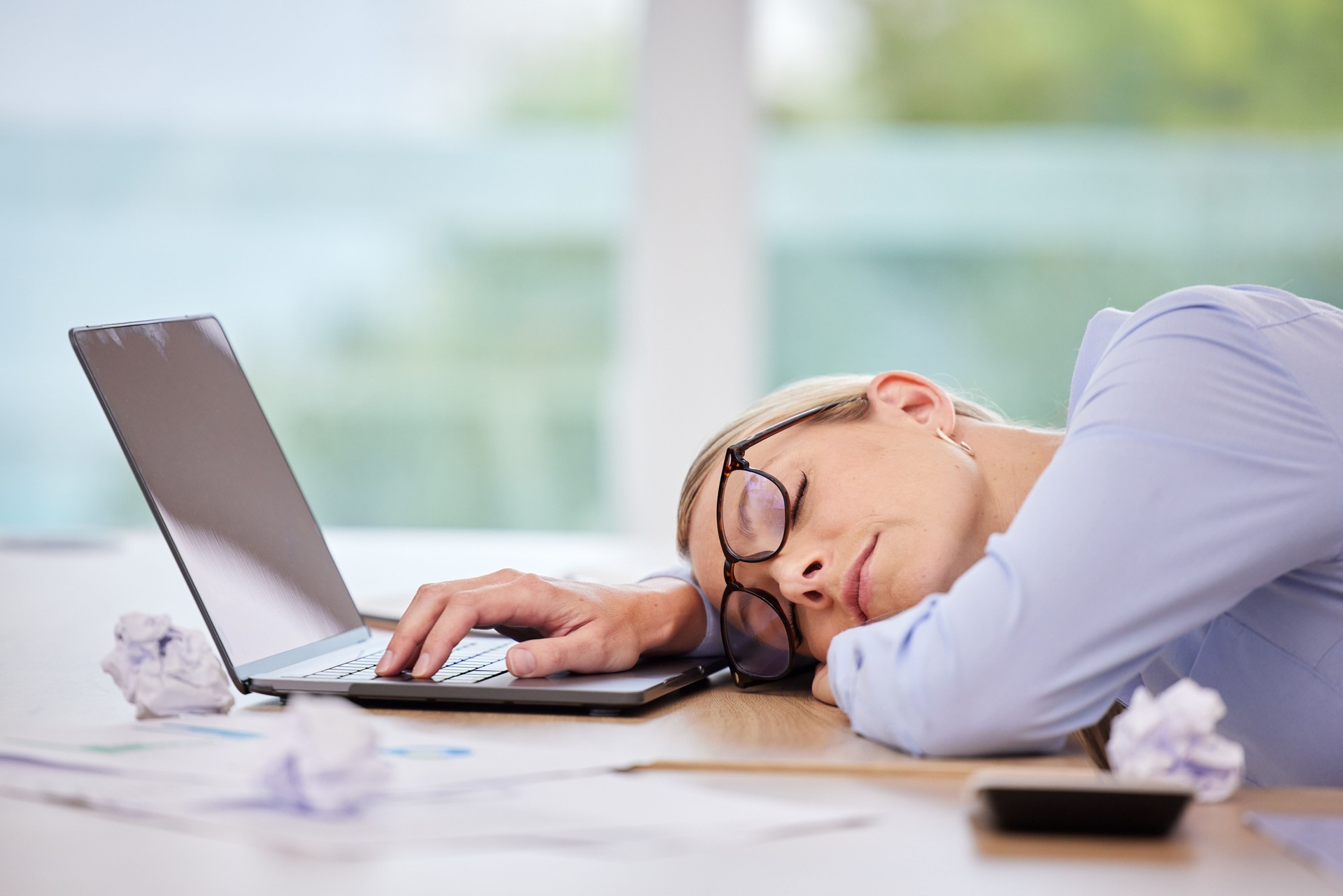 Business woman sleeping at laptop desk, burnout stress from fatigue and insomnia problem in workplace career at computer. Office worker tired, risk job loss and overworked person nap at tech company