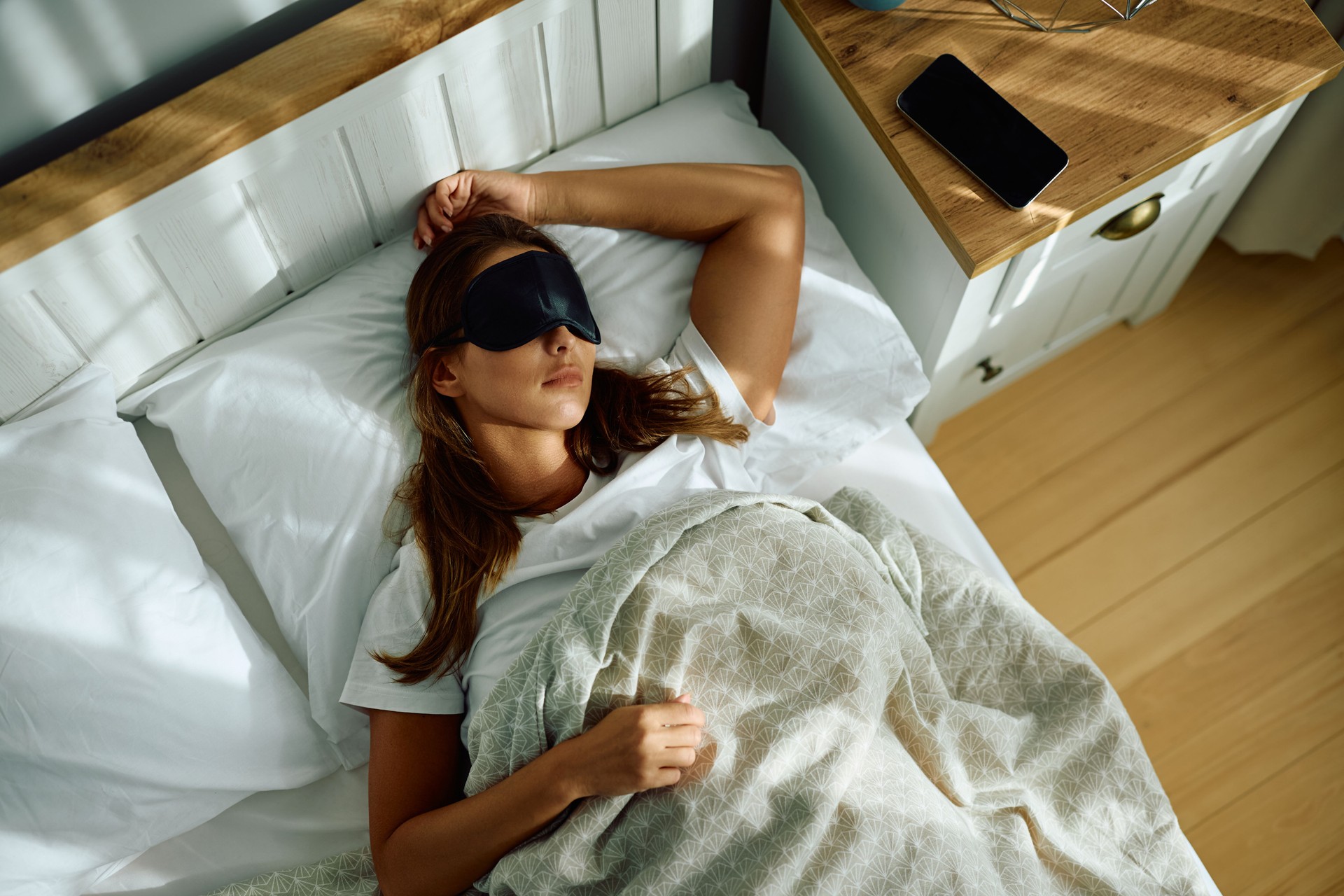 Above view of woman with eye mask sleeping in bed.